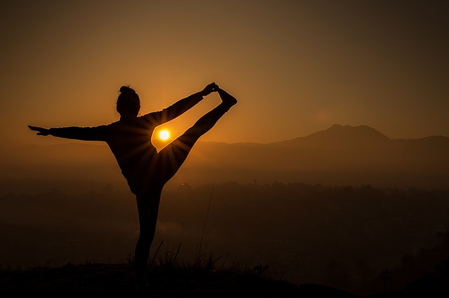 žena cvičí jógu při východu slunce